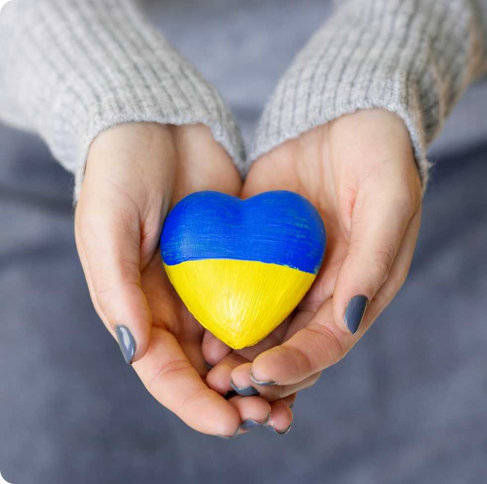 Symbolic Support: Colorful hands holding a flag-painted stone in solidarity with Ukraine